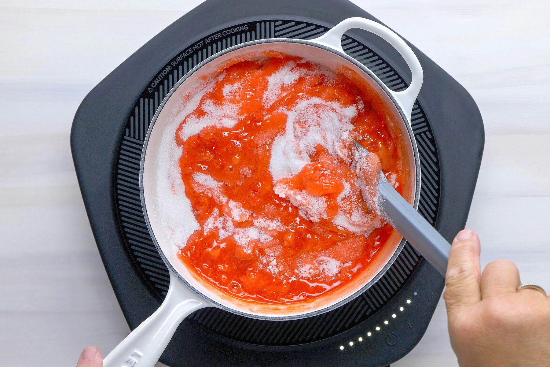 Overhead shot of the same saucepan; add sugar and return to a rolling boil; boil for 1 minute; stirring constantly; spatula; induction; wooden surface