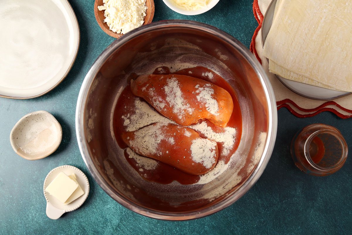 Process of making Taste of Home's Buffalo Chicken Egg Rolls. Chicken and buffalo sauce with ranch mix in a slow cooker.