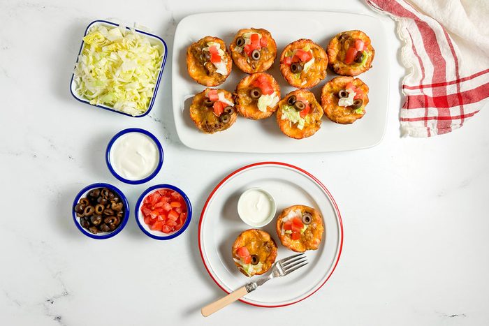 Taste of Home Taco Cups on an enamel plate on a marble surface with assorted toppings