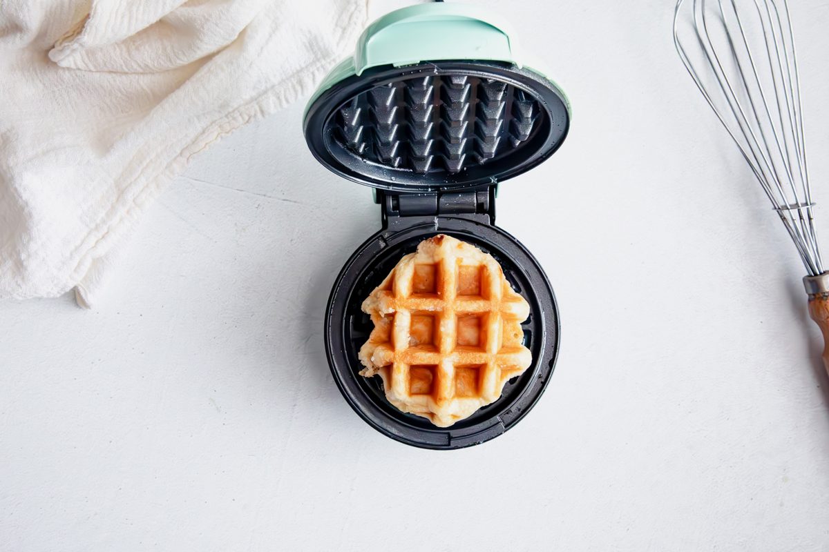 Batter in waffle iron for Taste of Home Waffle Cookies on a marble surface.