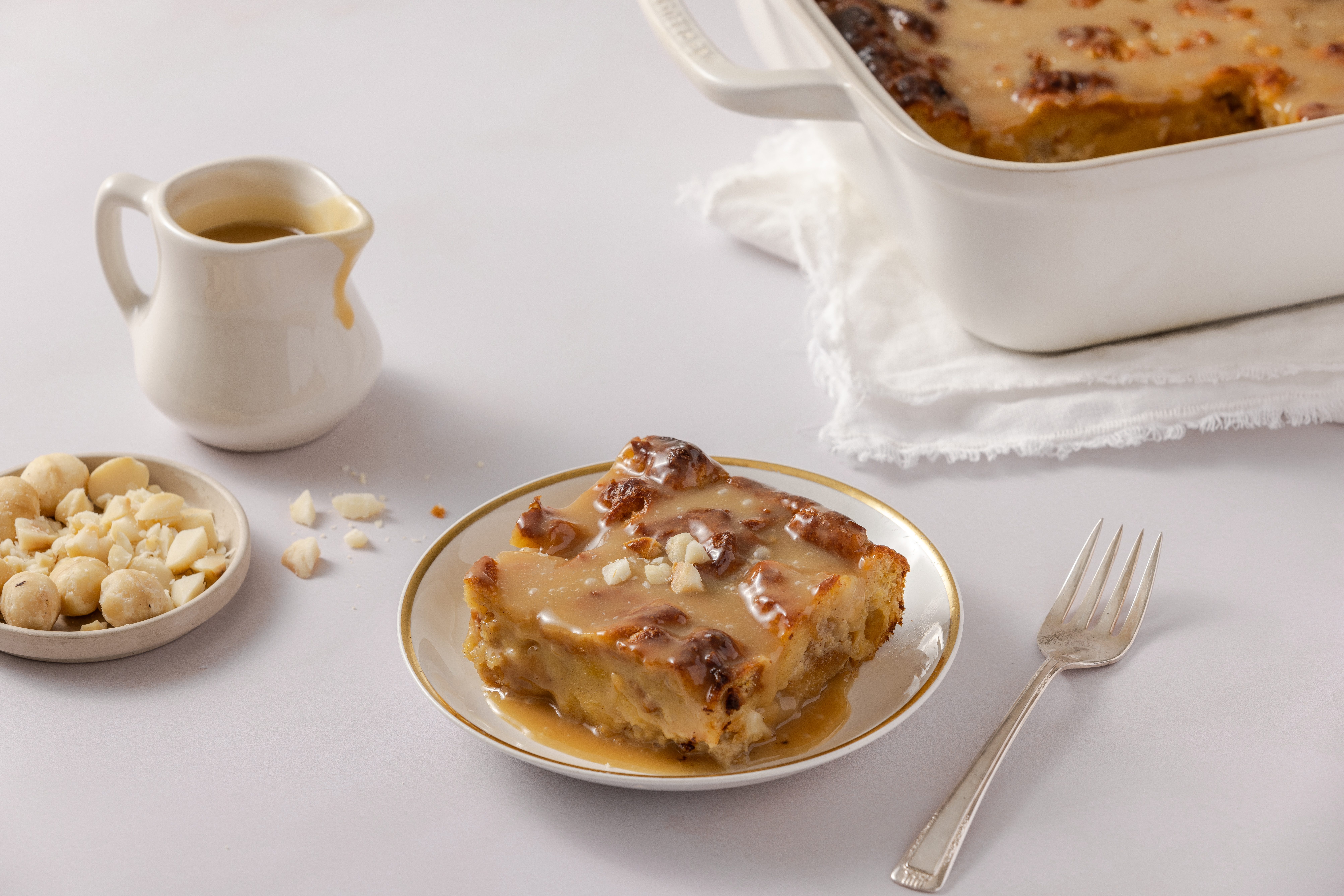 Bread pudding served on plate, garnished with chopped macadamias.