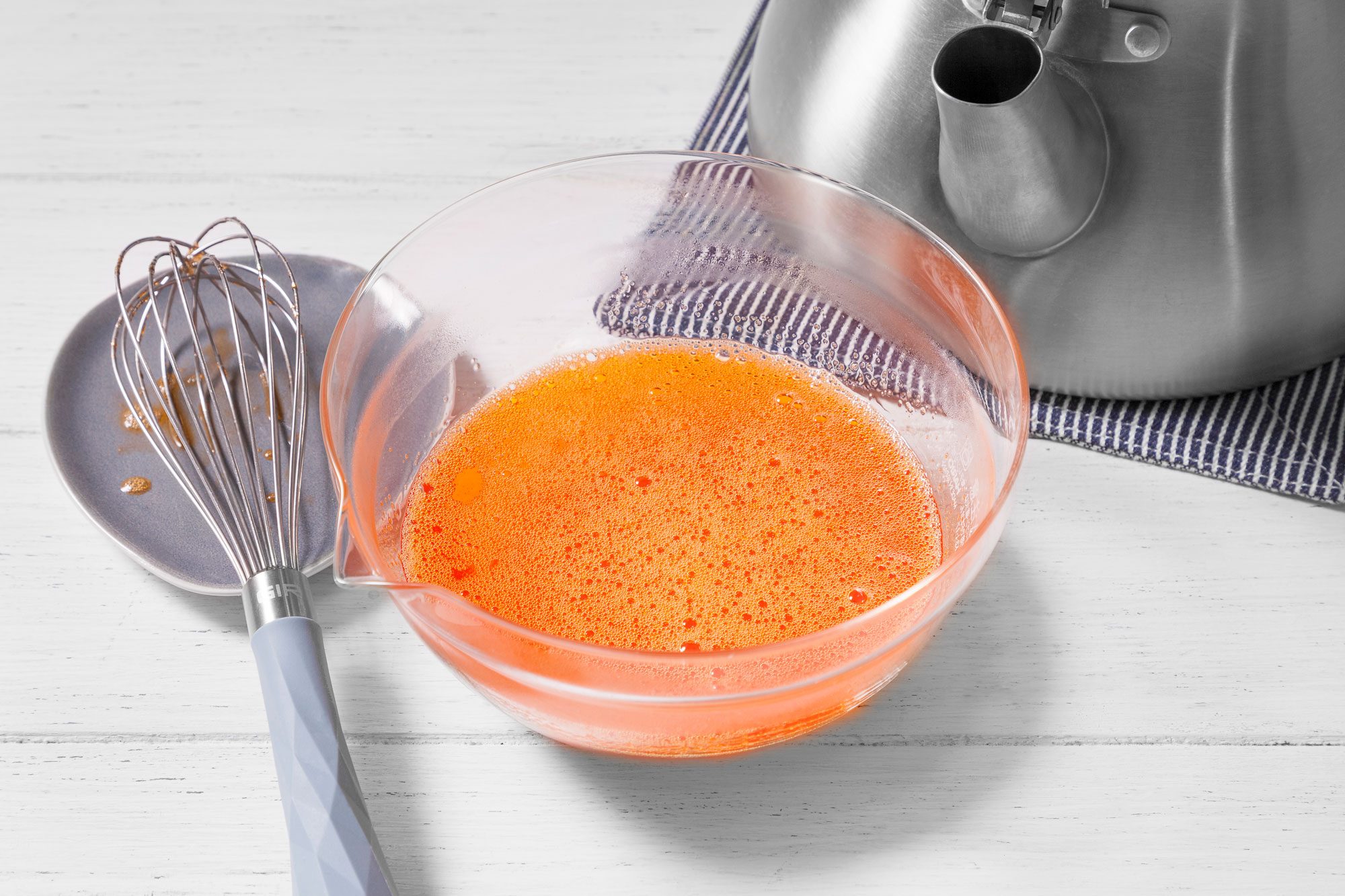 A bowl of orange liquid with bubbles in it