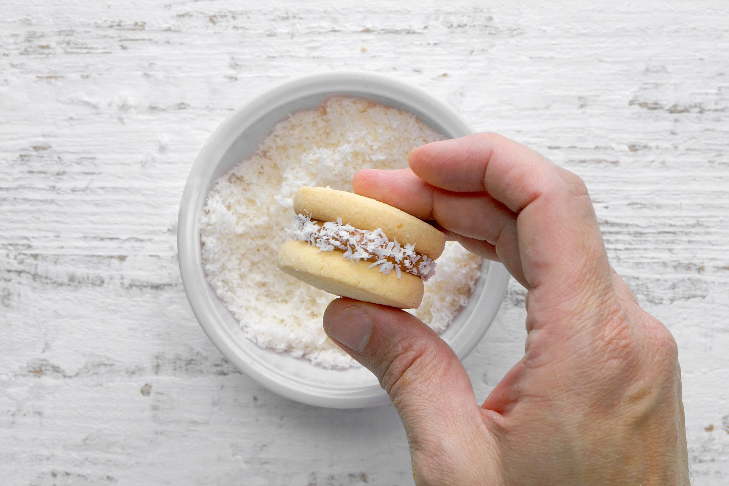 Rolling the edges of Alfajores in coconut