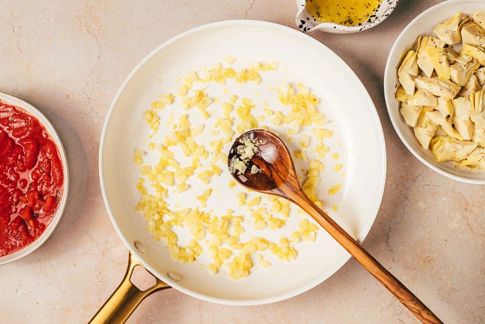 Cooking the onion and garlic in a large skillet for the Artichoke Tomato Pasta Recipe by Taste of Home
