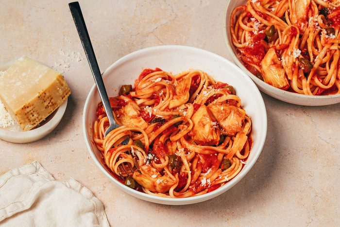 Two bowls with Artichoke Tomato Pasta topped with grated parmesan recipe by Taste of Home