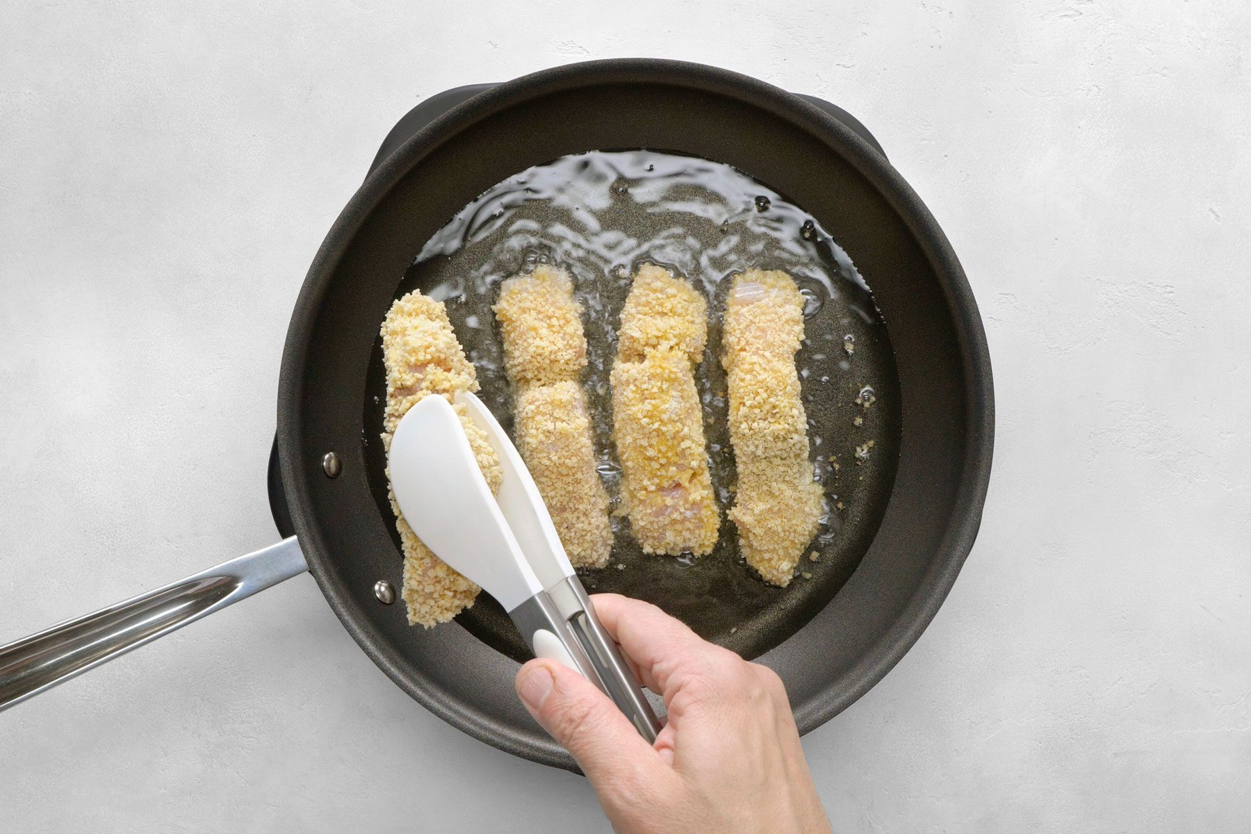 fish strips being fried in a large skillet