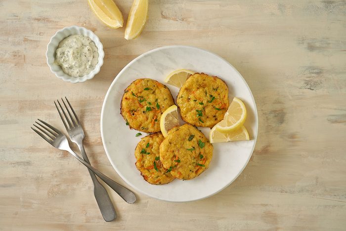 Overhead hero shot of the finished Taste of Home Baked Crab Cakes, golden brown and crispy, served with a side of tartar sauce and a wedge of lemon.
