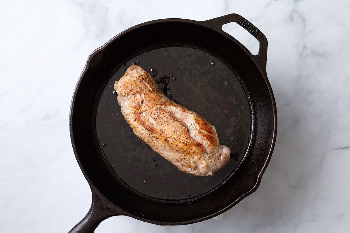 Pork tenderloin seared in a cast iron skillet for step two of Balsamic Pork Tenderloin for Taste of Home