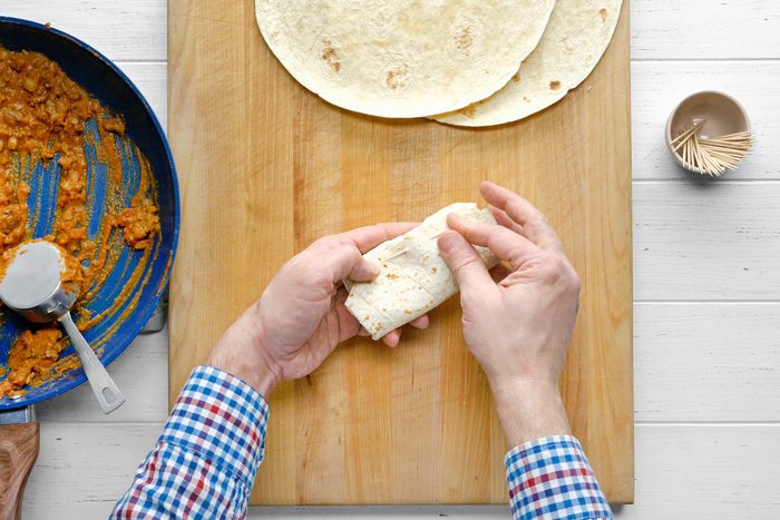Folded tortilla being fastened with toothpick.