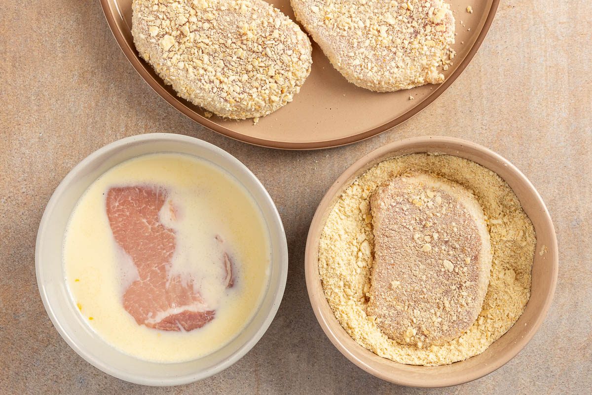 dredging the pork chops by dipping it in egg and bread crumbs