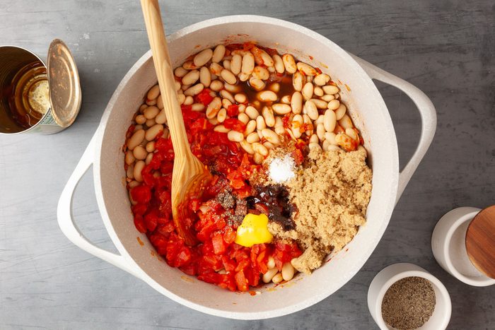 Step 2 of Taste of Home British Baked Beans is to Stir in the navy beans, diced tomatoes, brown sugar, molasses, yellow mustard, cider vinegar, Worcestershire sauce, salt and pepper. Bring to a gentle simmer and cook for 15 to 20 minutes until the sauce is thick.