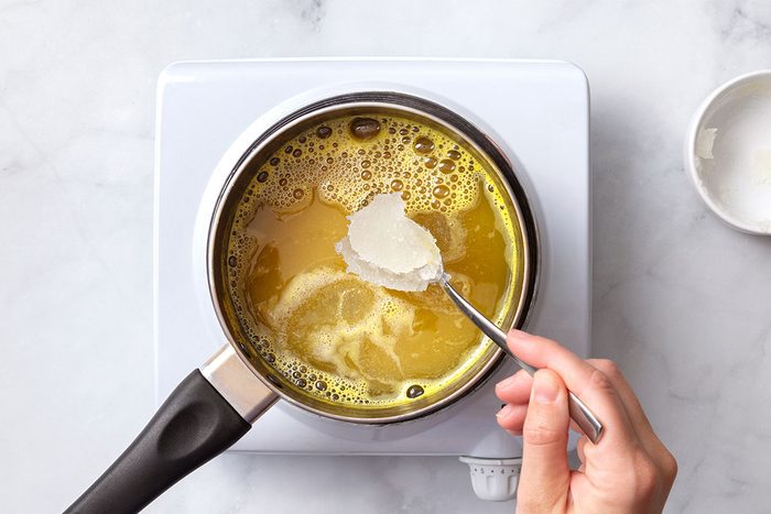 Unflavored gelatin being added to boiling pineapple juice in a saucepan for step two of Broken Glass Jello recipe for Taste of Home