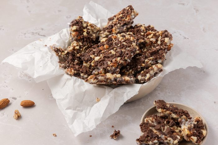 Butter toffee broken into pieces and served in bowl.