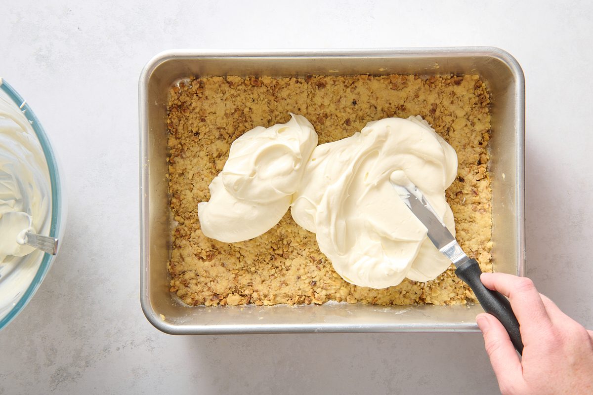 Spreading cream cheese layer over crust