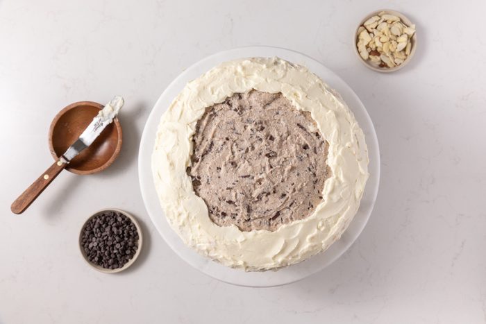 Cake layers being assembled and finished with frosting.