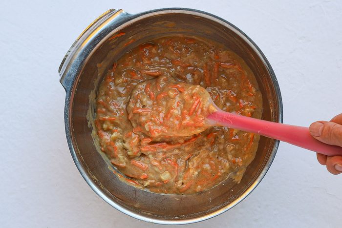 Folding carrots and pineapple into carrot cake batter.