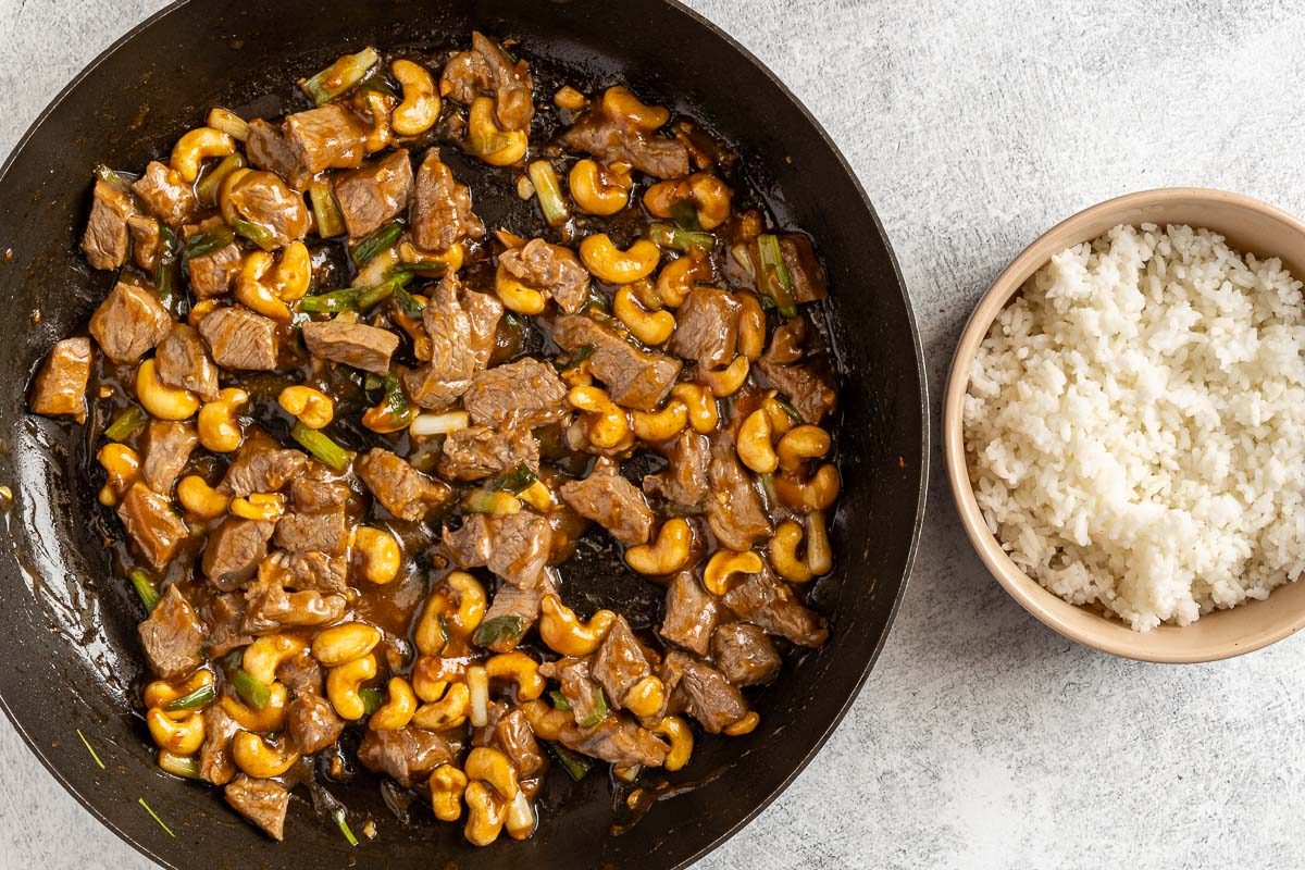 Taste of Home Cashew Beef photo of the stir fry with the thickened sauce and a bowl of rice.