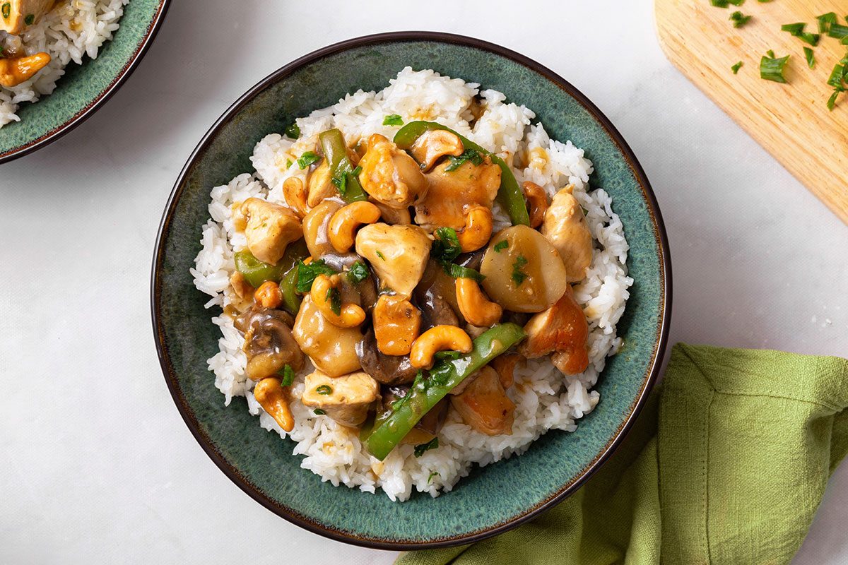 Overhead view of Cashew Chicken stir fry on top of hot rice in a serving bowl for Cashew Chicken recipe for Taste of Home