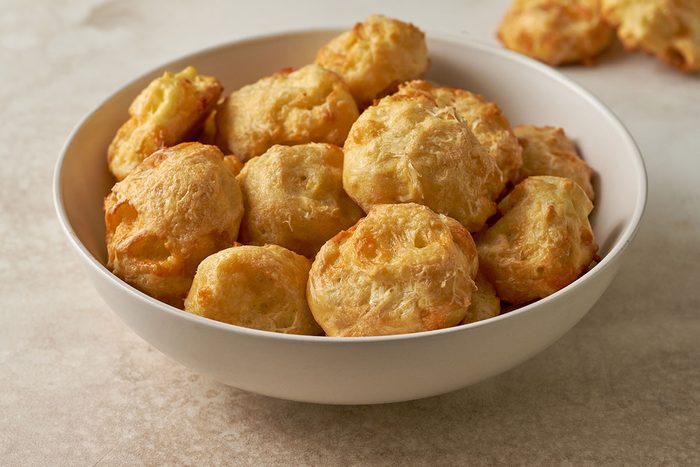 A close-up shot of a Cheese Puff, highlighting the golden exterior and light, airy texture inside, by Taste of Home.