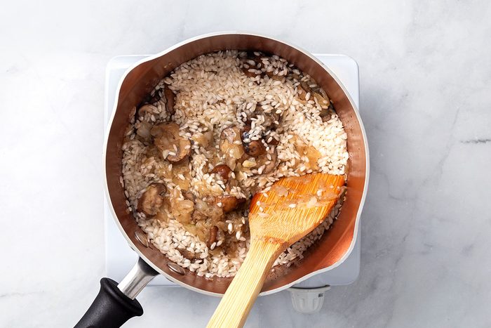 Arborio rice added to a saucepan with tender mushrooms and onion for step three of Chicken Risotto recipe for Taste of Home