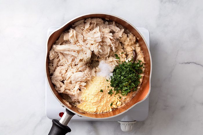 Shredded rotisserie chicken, grated parmesan, minced parsley and salt added to risotto mixture for step five of Chicken Risotto recipe for Taste of Home