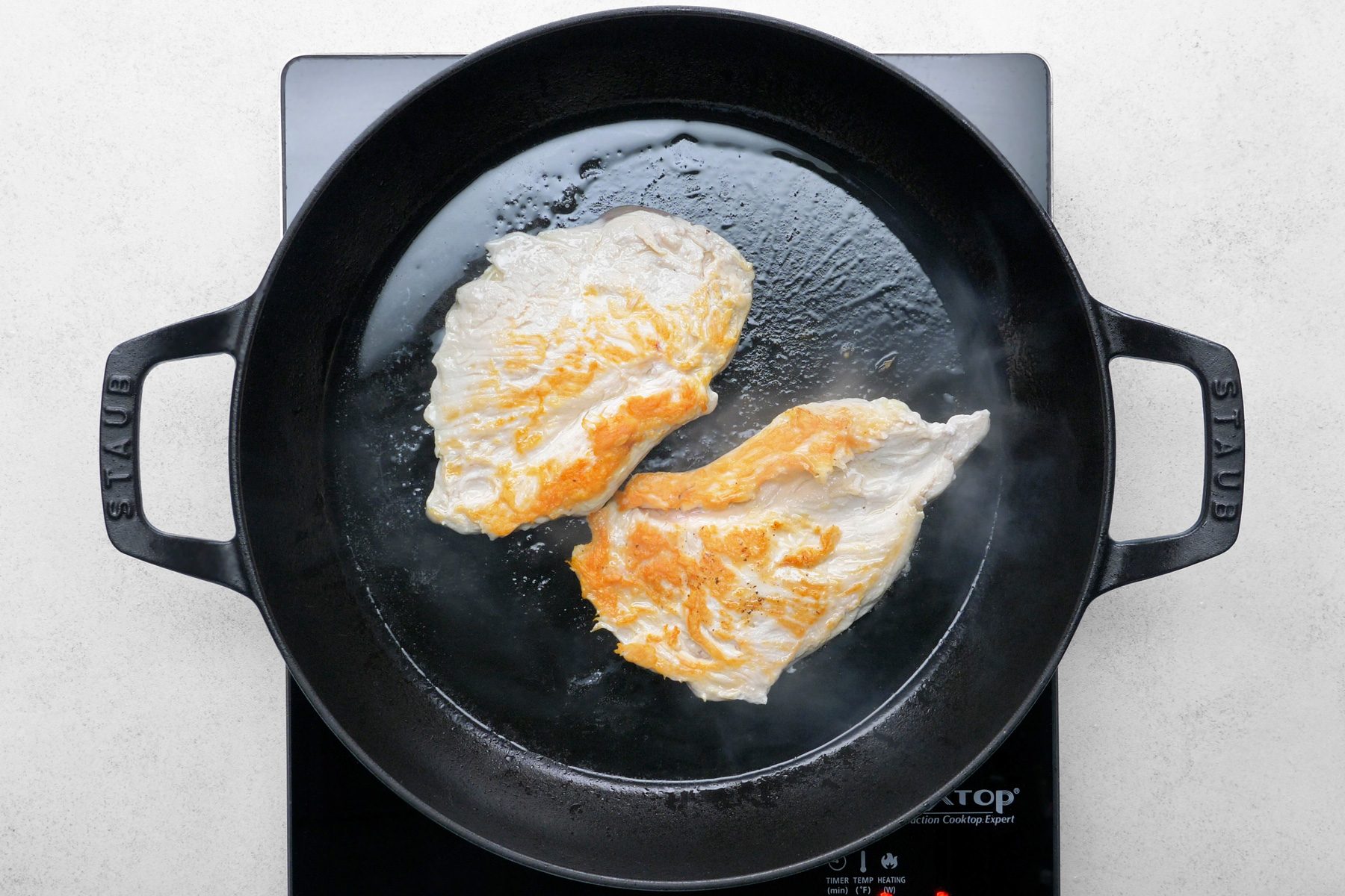 In a large nonstick skillet, the chicken is being cooked until it is no longer pink in the center.