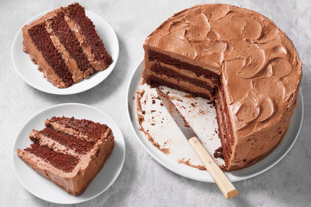 Chocolate Cake cut with some slices on plates nearby