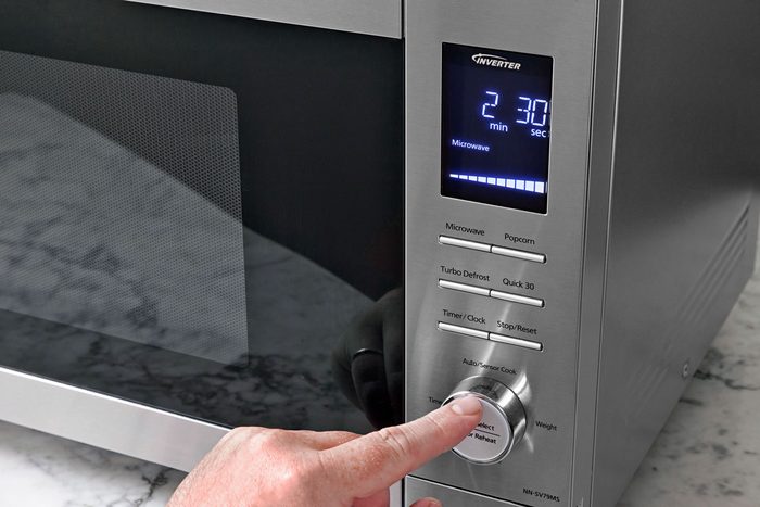 A hand can be seen adjusting microwave settings.