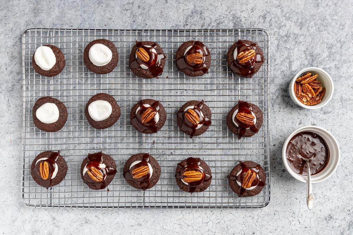 baked cookies topped with icing and a pecan.