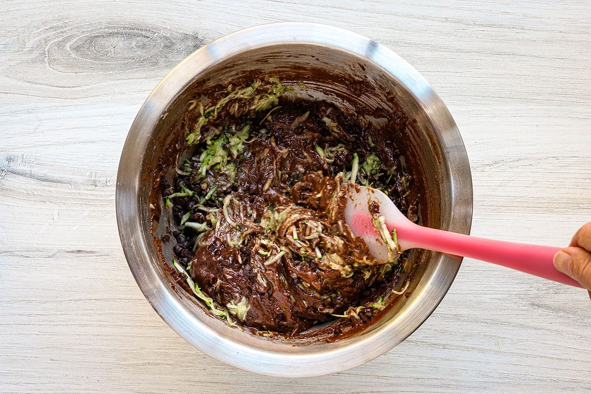 Folding shredded zuccini and chocolate chips into the chocolate muffin batter.