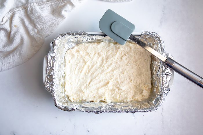 Overhead shot for Taste of Home Coconut Snowballs, coconut snowball mixture pressed into baking dish with tin foil.