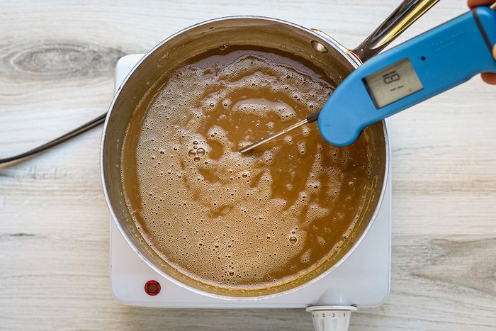 A saucepan with custard for coffee ice cream, with an instant read thermometer checking the temperature.