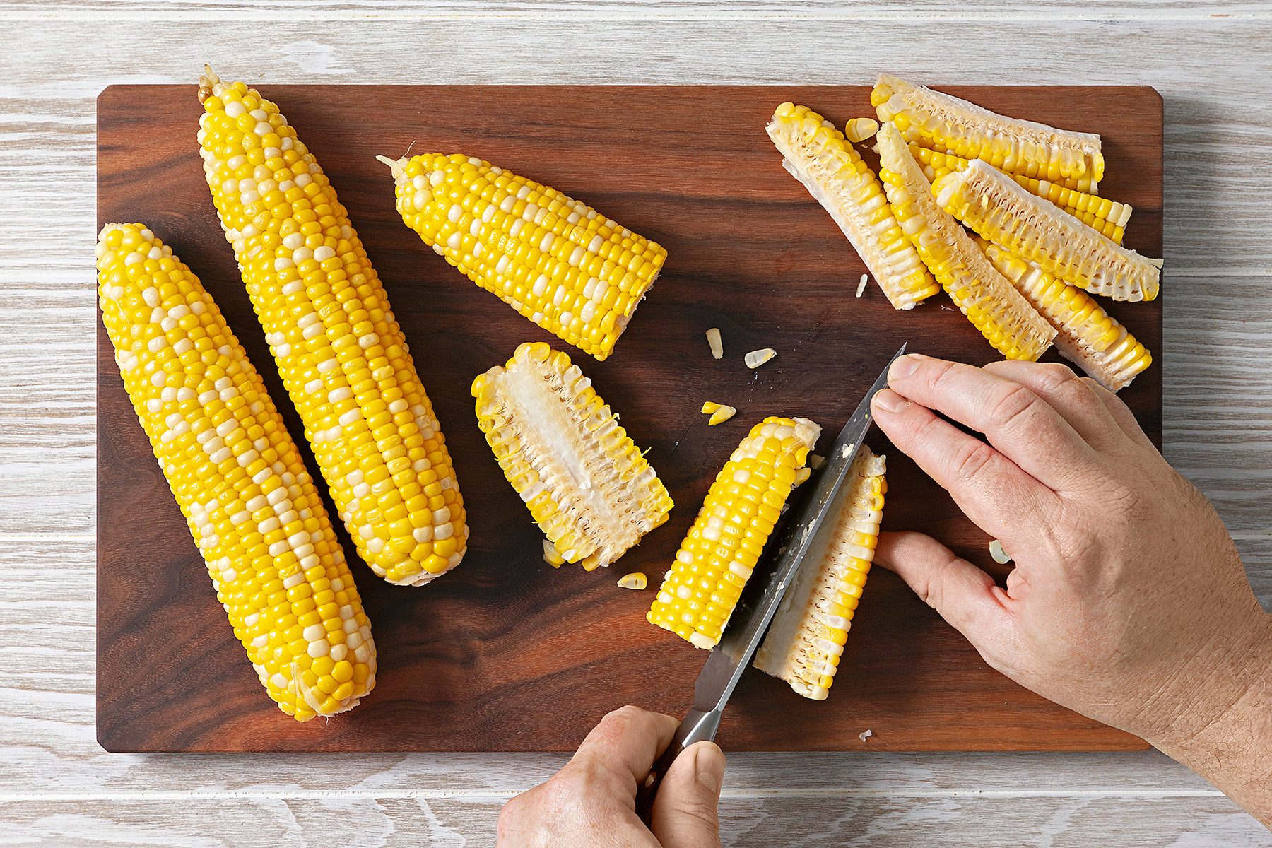 Overhead shot of slice each half into quarters; knife; wooden chopping board; wooden surface;