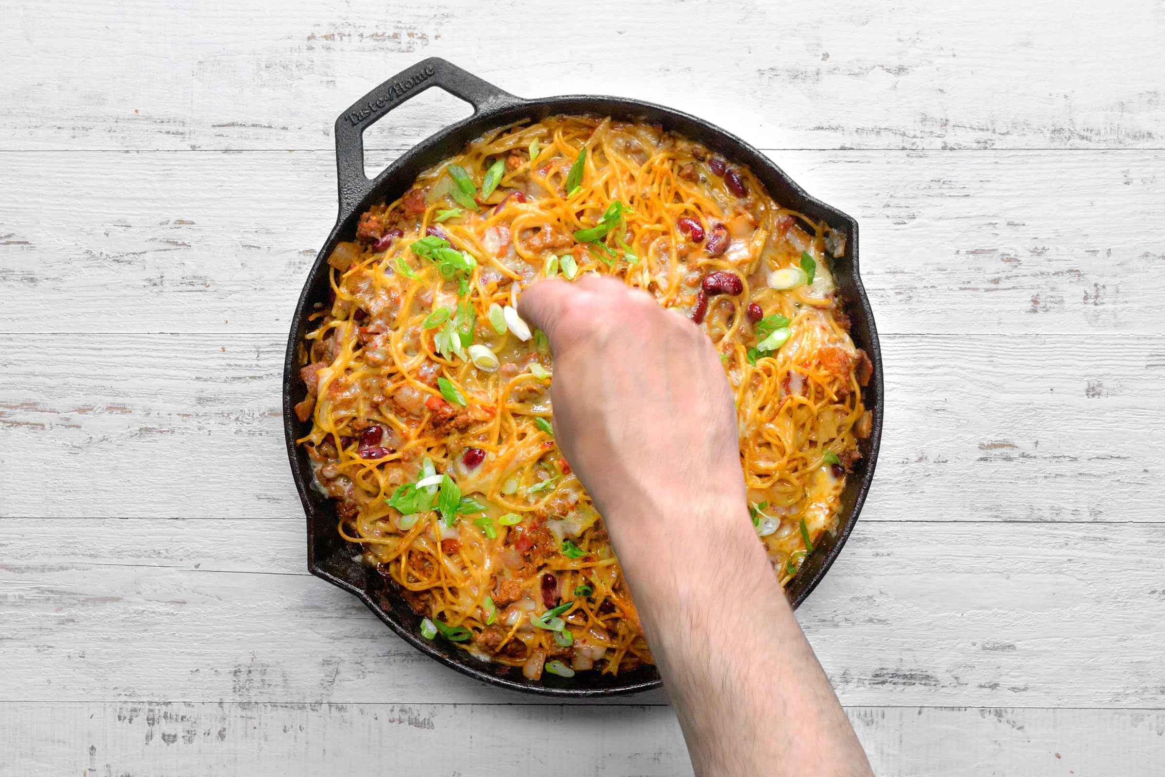 Sprinkling green onions on Cowboy Spaghetti