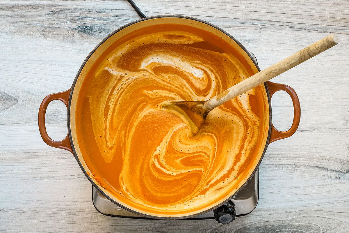 Stirring cream into a pot of carrot soup.