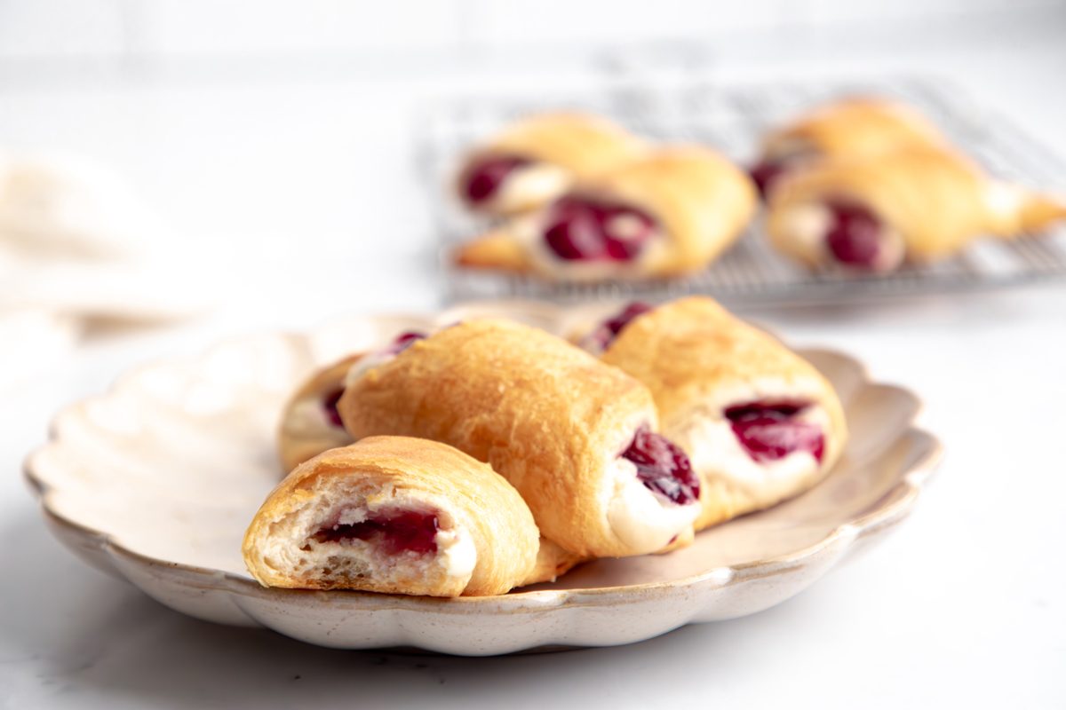 Beauty shot for Taste of Crescent Rolls with Cherry Pie Filling, baked crescent rolls with cream cheese and cherry filling inside on a scalloped plate showing texture.