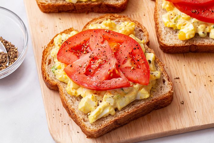 Whole wheat bread slice topped with Curried Egg Salad and seasoned tomato slices for Taste of Home