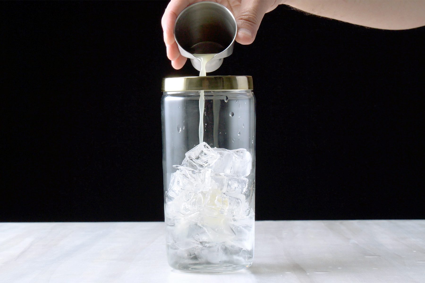 Table view shot of fill a shaker three-fourths full with ice; add remaining ingredients; white base;