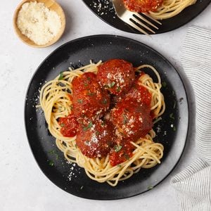 Two single servings of Taste of Home Lentil Meatballs in marinara sauce, on spaghetti, garnished with parmesan and parsley