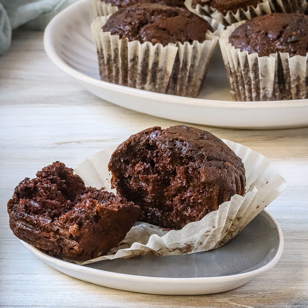 A chocolate zucchini muffin with several in the background, from a recipe by Taste of Home.