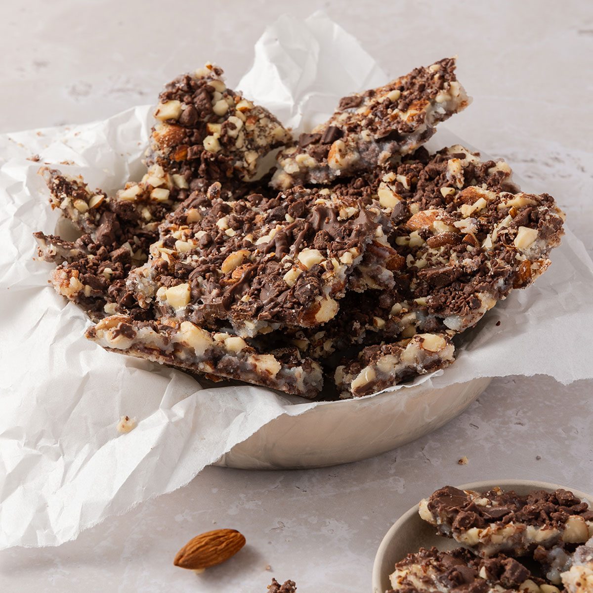 Butter toffee broken into pieces and served in bowl.