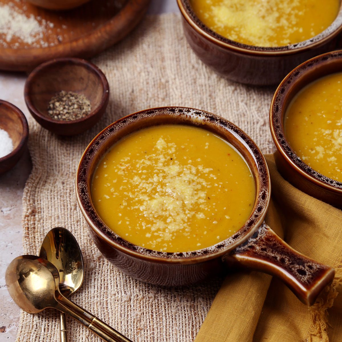 Close up of Taste of Home's butternut squash and sweet potato soup served in brown soup crocks on a brown marble surface.