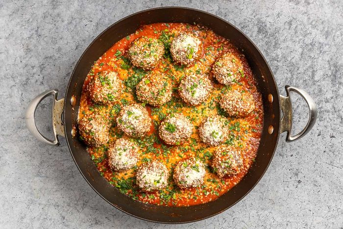 Taste of Home Gluten Free Meatballs recipe photo of the cooked meatballs in a skillet topped with marinara sauce, Parmesan cheese and fresh parsley.