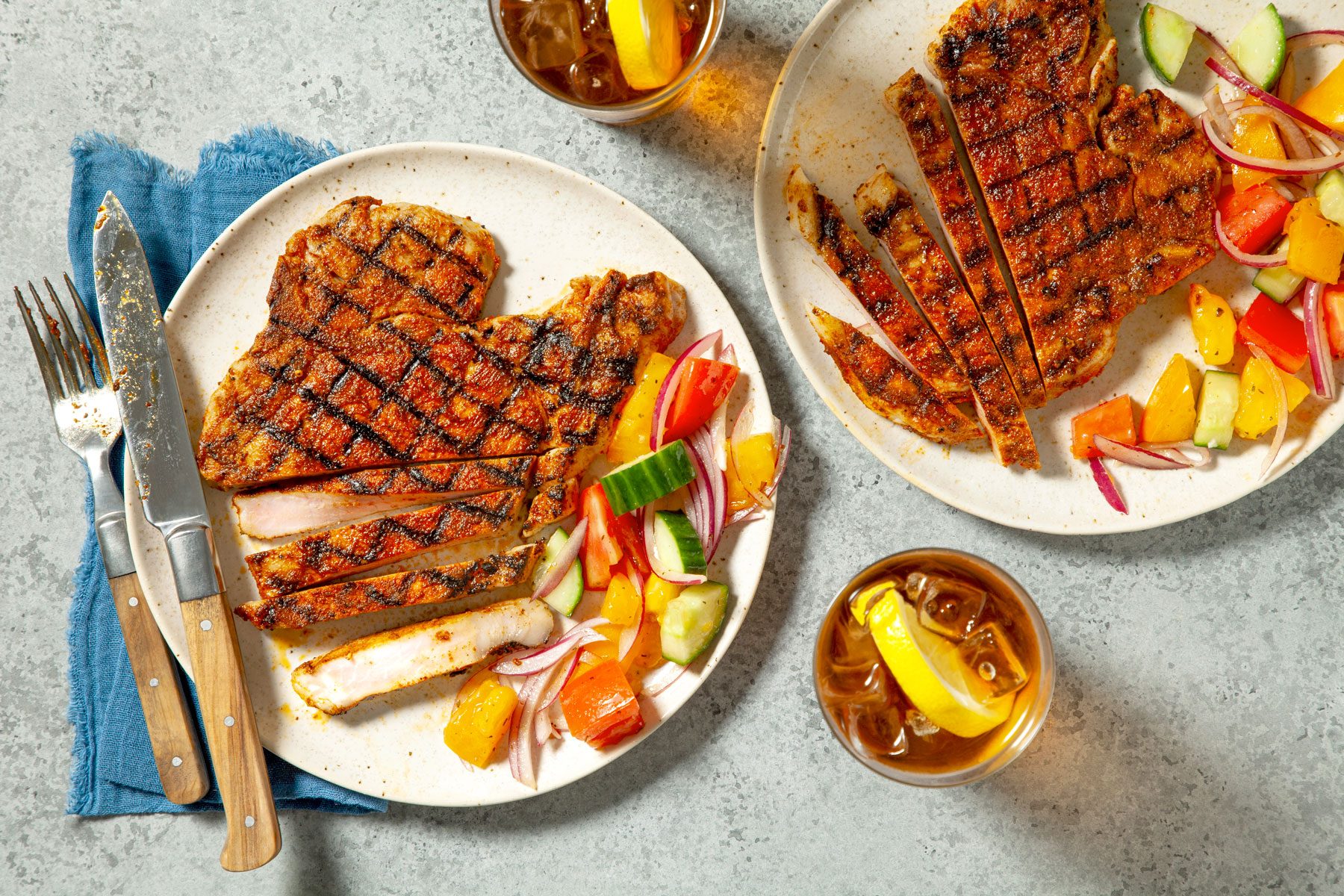 Two plates with grilled Pork Chops served with salad and drinks.