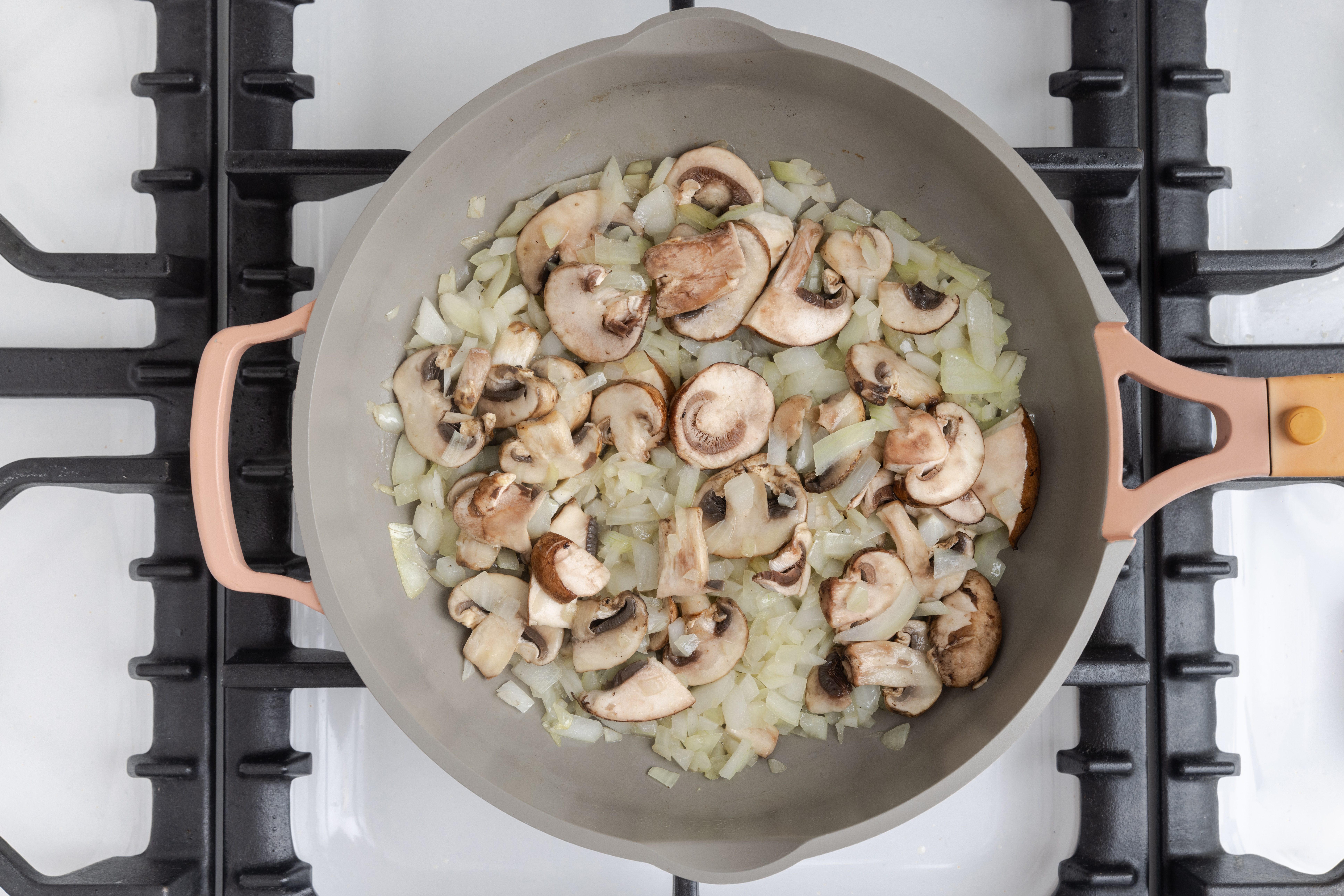 Onions and mushrooms being cooked in skillet.