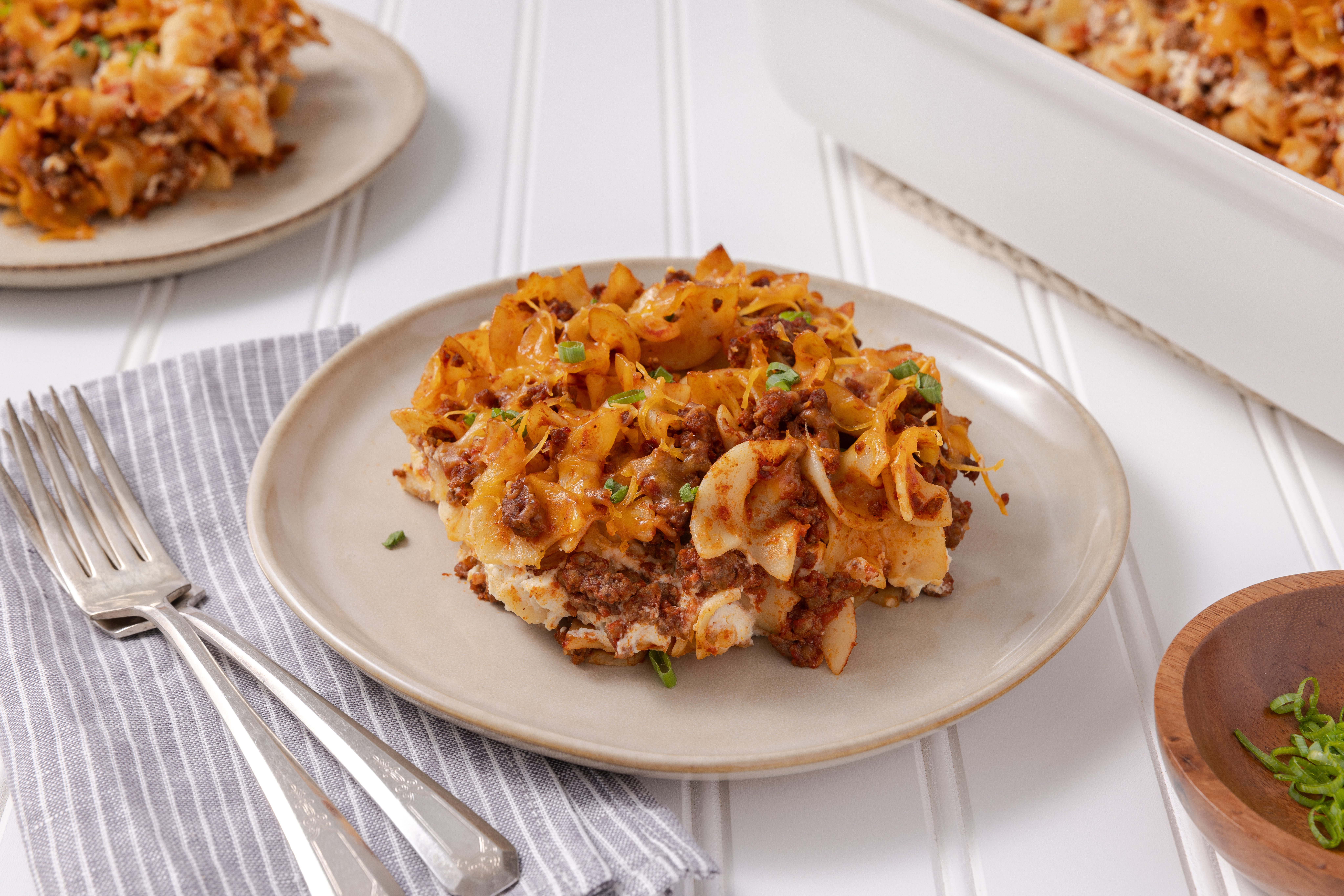 Casserole served on plate with baking dish in the background.
