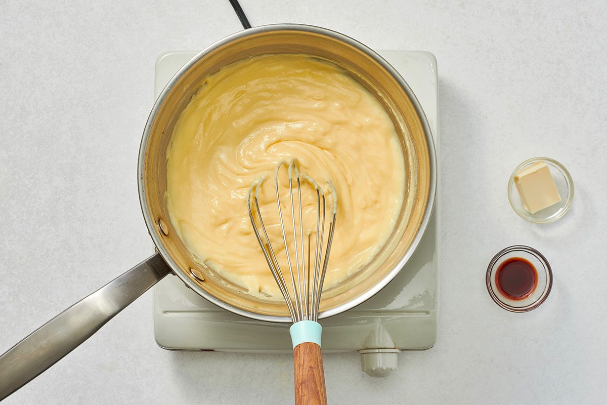 Cooking custard in a saucepan with butter and vanilla extract nearby