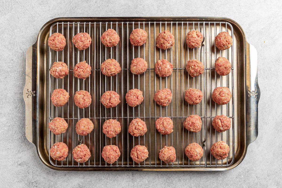 formed shaped meatballs on a rack on a shallow baking pan