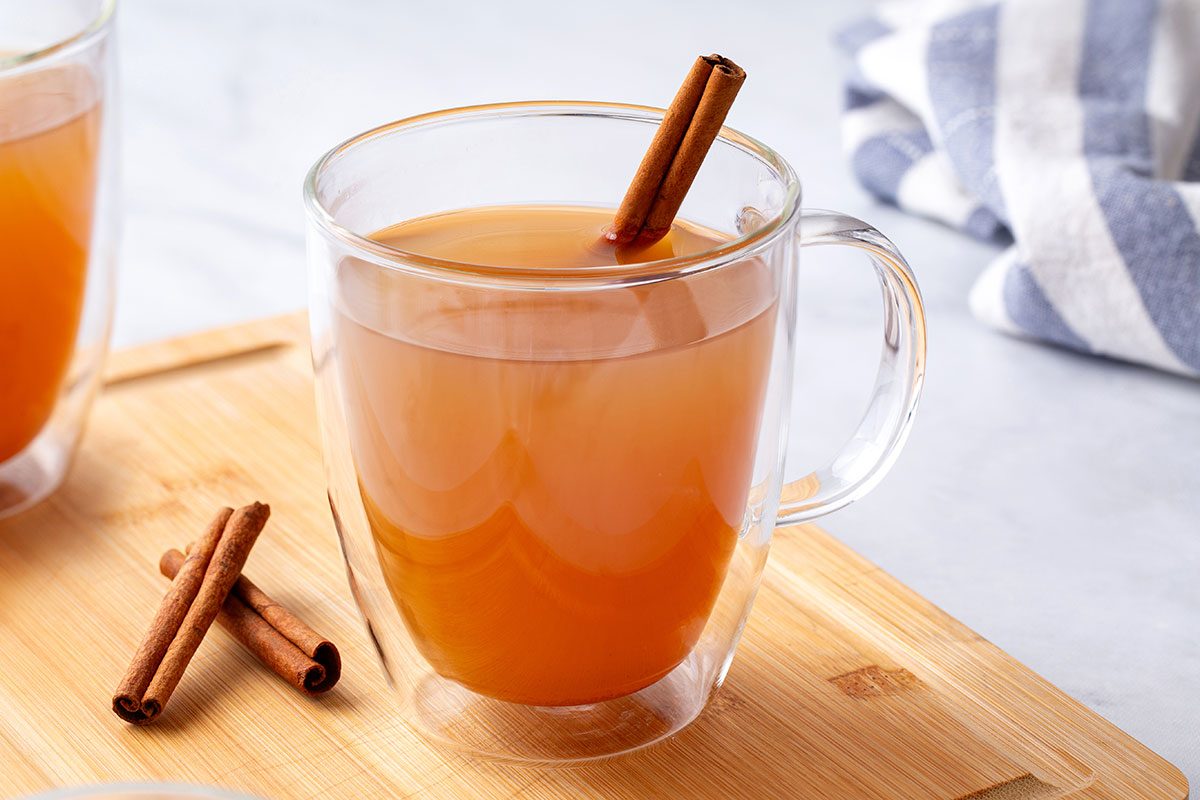 Hot Apple Cider in clear mug glasses with a cinnamon stick for Taste of Home