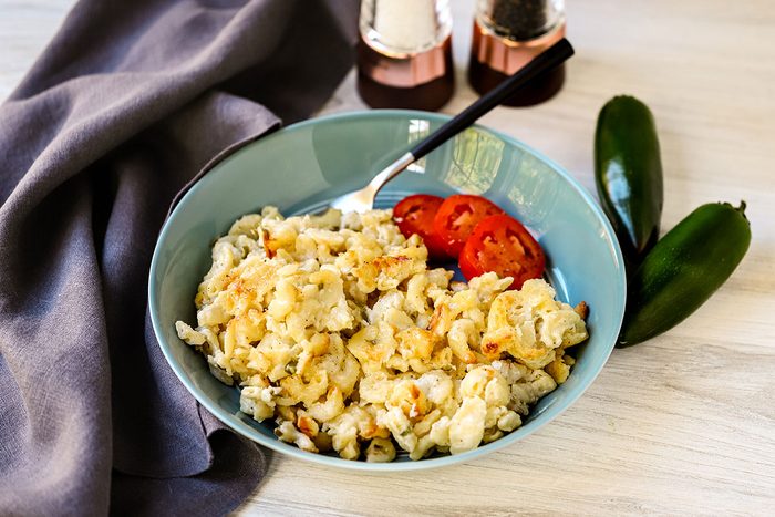 A serving of jalapeno mac and cheese with sliced tomatoes on the side.